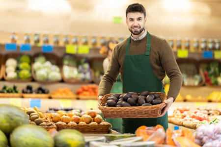 Young man seller puts avocado in store