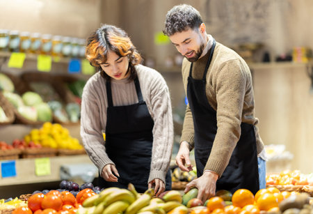 Portrait of man and woman - employees of grocery supermarket with various vegetables and fruits in their handsの写真素材