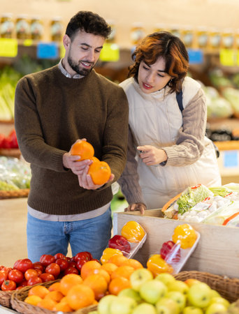Young couple choose oranges in storeの写真素材