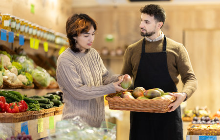 Male salesperson offers a female customer mango for saleの写真素材