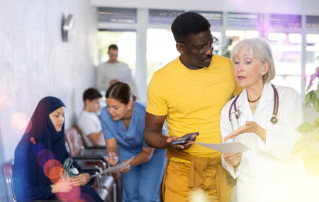 Elderly female medic giving document to african man for signingの写真素材