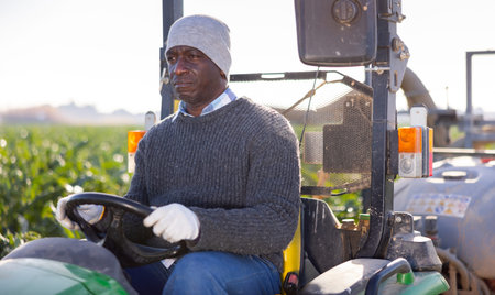 Farmer working on farm tractor at the fieldの写真素材