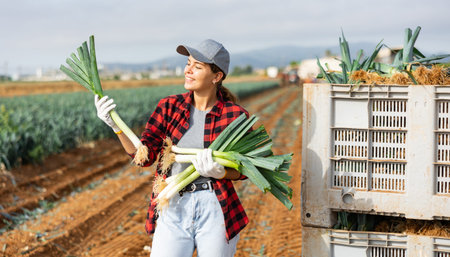 Woman posing with leek crop on fieldの写真素材
