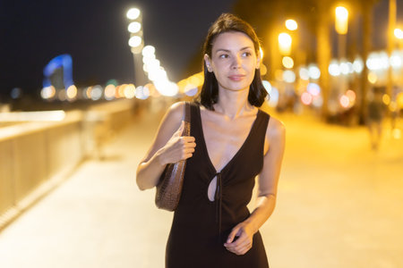 At night, slender female brunette walks in vicinity of beach in Barcelonetaの写真素材