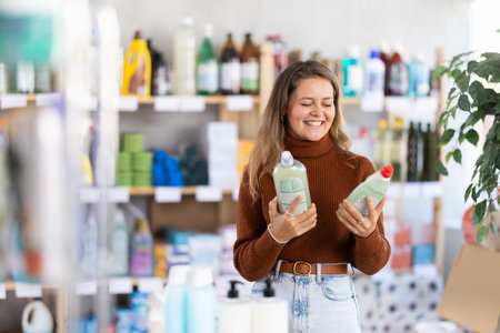 Young woman chooses dishwashing detergent in storeの写真素材