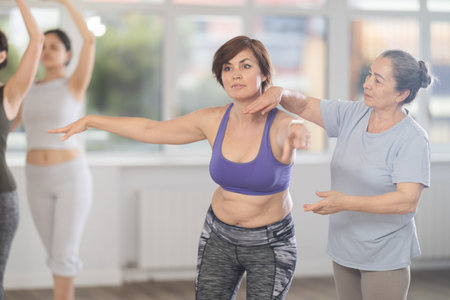 Elderly woman teacher correcting female dancers