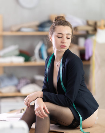 Girl in stockings sits on table in sewing workshopの写真素材