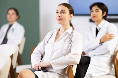 Diligent woman medical student with group of other interns listening lecture at lesson in universityの写真素材