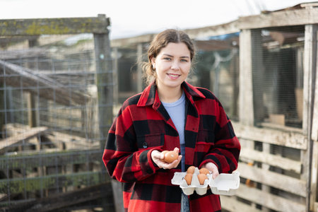 Positive woman stands and holds in hands palms few fresh chicken eggs