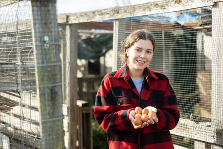Positive girl stands and holds in hands palms few fresh chicken eggsの写真素材
