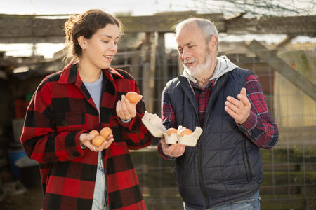 Girl with senior father presents farms eco-friendly products - chicken eggsの写真素材
