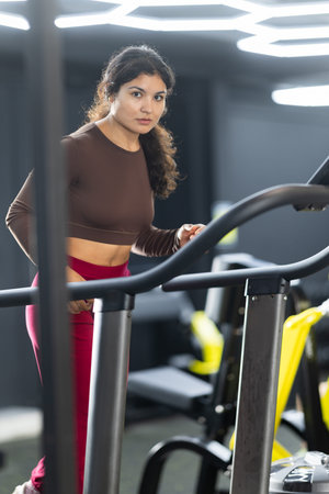 Sportive Latina girl training on treadmill in gym