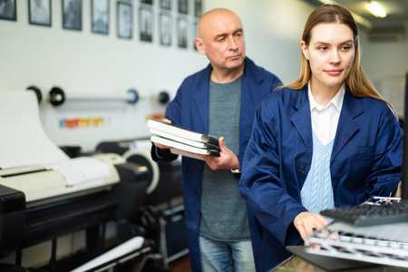 Female employee of the printing house adjusts the plotter using computer