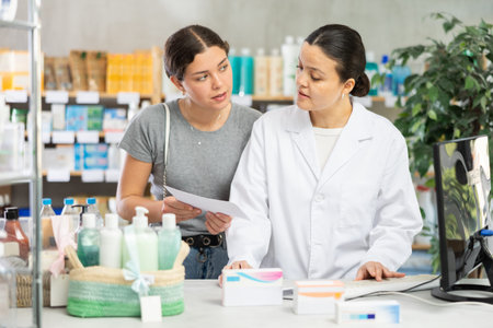 Young female pharmacist working on computer Asian client standing behind in chemistryの写真素材