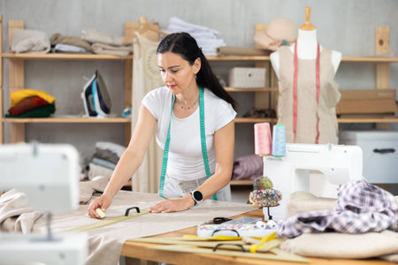 Woman tailor draws dress pattern of product on paper