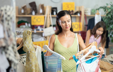 Middle-aged woman choosing something for summer in clothing store