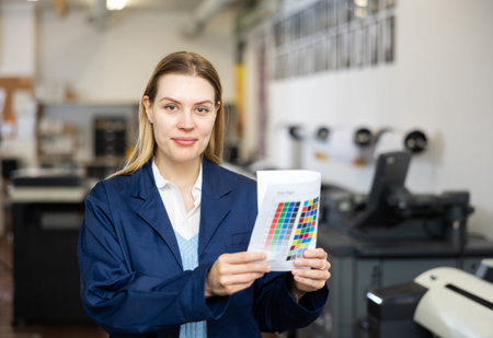 Woman employee of printing shop holds color chart in her hands