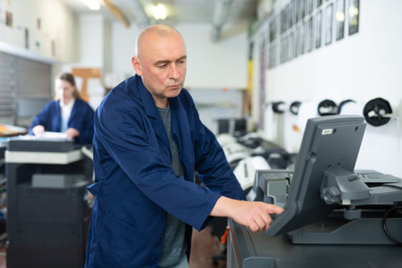 Printing house employee works on printing equipment