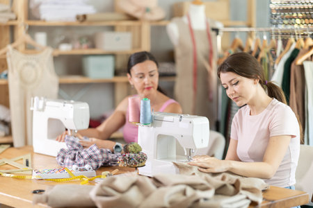 Two seamstresses working on sewing machines in sewing workshop