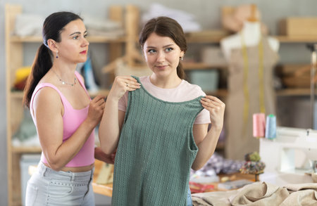 Girl customer examines finished product in presence of female tailorの写真素材