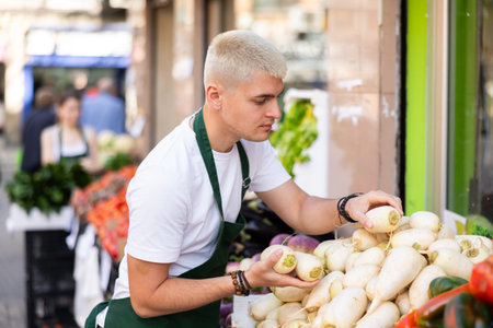 Grocery store employee places ripe radish on a display case at street store