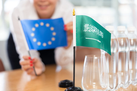 Flags of EU and Saudi Arabia stand on negotiating table in office