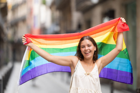 Woman waving LGBT flag on street of summer city