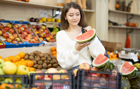 Young woman choosing watermelon at vegetable marketの写真素材