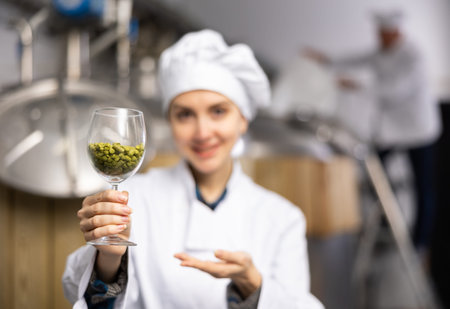 Female brewer holding glass with hops pelletsの写真素材
