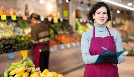 Woman seller take inventory with list in vegetable shopの写真素材