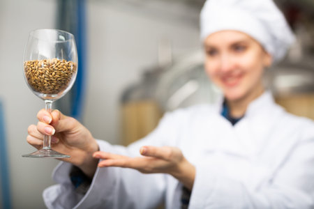Woman brewer showing malted grain for craft beer production