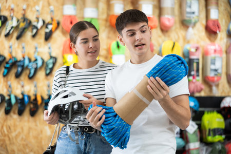 Guy and girl view rope cable for climbing and evaluate its thickness