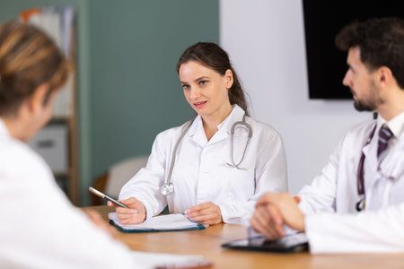 Representatives of medical professional community sitting at table and chattingの写真素材