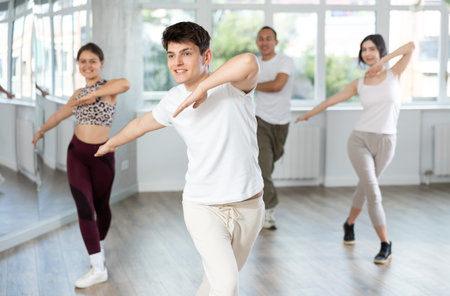 Smiling young people practicing vigorous lindy hop movements in dance class