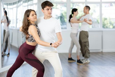 Smiling young woman and partner successfully perform mesmerizing movements of paso doble dance...