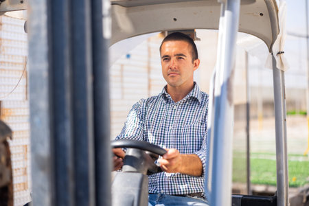 Middle aged man working on forklift in greenhouse