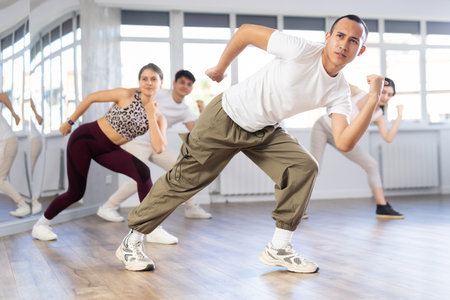 Positive young men and girls dancing modern street dance together during their group training at...
