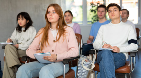 Young female student listening to lecture with focus