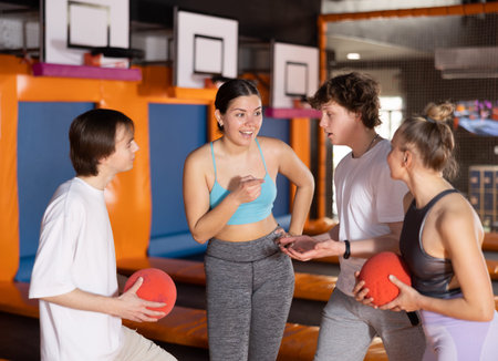 Group portrait of enthusiastic young people discussing upcoming jumping workout on trampoline in...
