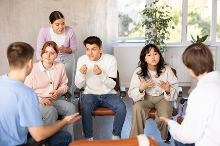 Group of students sitting in circle studying together in study hall of university