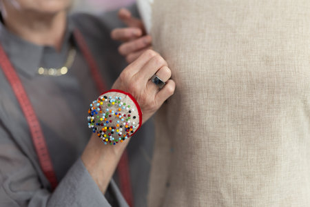 Hands of an experienced seamstress with a pin pad