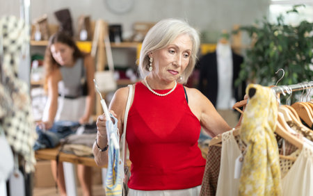 Elderly woman choosing vest in clothing store