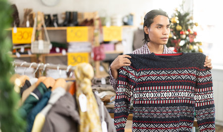 In chain shop, Indonesian man choose sweater, X mas shopping
