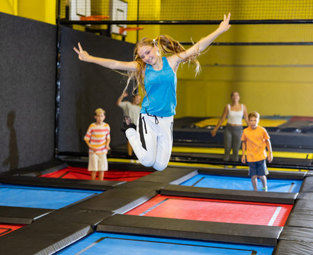 Teenage girl having fun jumping in indoor trampoline arena