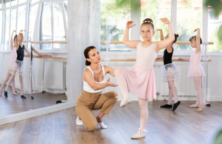 Woman teacher corrects movement of girl dancer