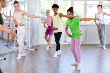 Amateur teenage girl practicing ballet positions standing in row with others