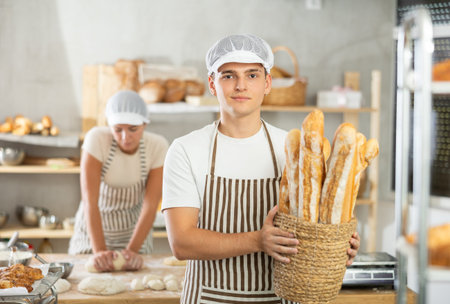 Enthusiastic young baker presenting freshly baked golden baguettes