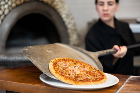 Woman chef putting fresh pizza to plate