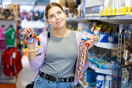 Young girl choosing toy for cat or puppy in pet store