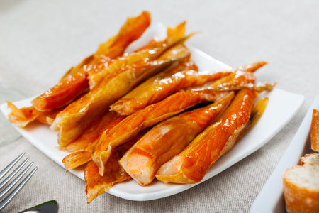 Smoked salmon belly strips on plate on wooden table